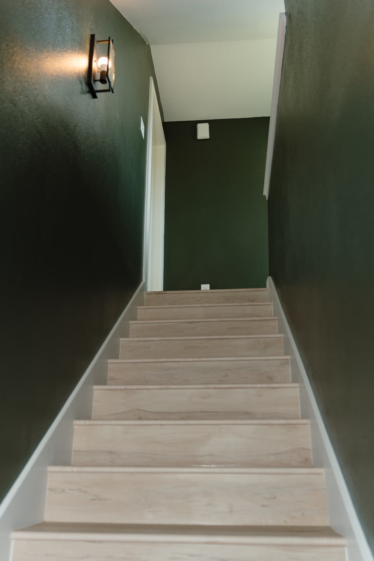 Stairwell with deep green walls and light wood treads