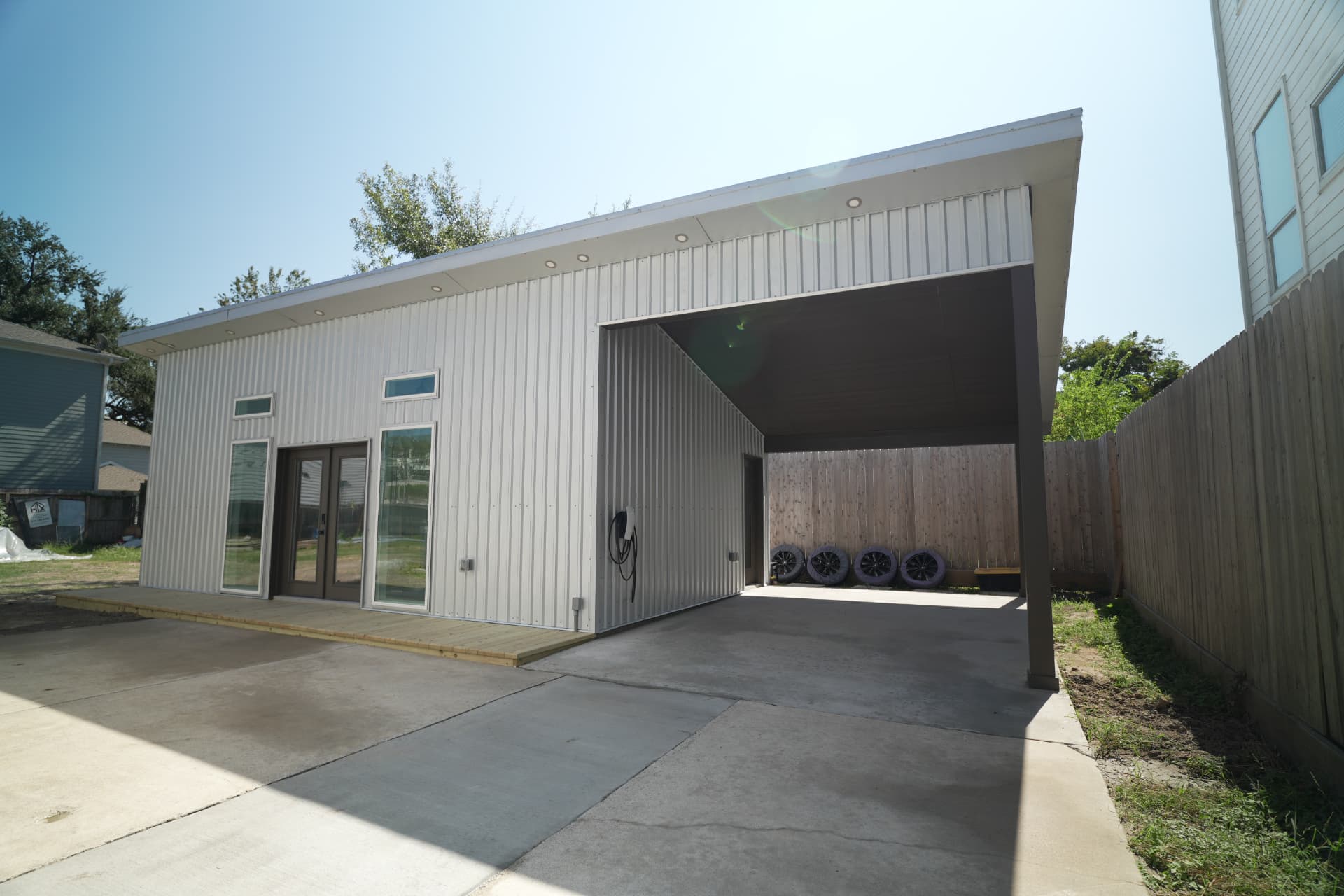 Metal-clad backyard tiny home with attached carport built by HTX Tiny Homes